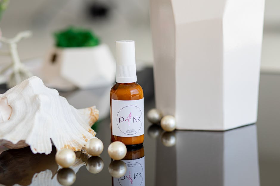 Home Chic still life featuring a cosmetic spray bottle with pearls and seashell on a reflective surface.