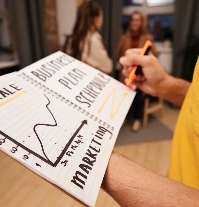 Close-up of a business notebook with marketing plans in a casual office environment.
